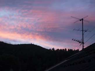 Antenne TV silhouettée contre un ciel crépusculaire rose et violet