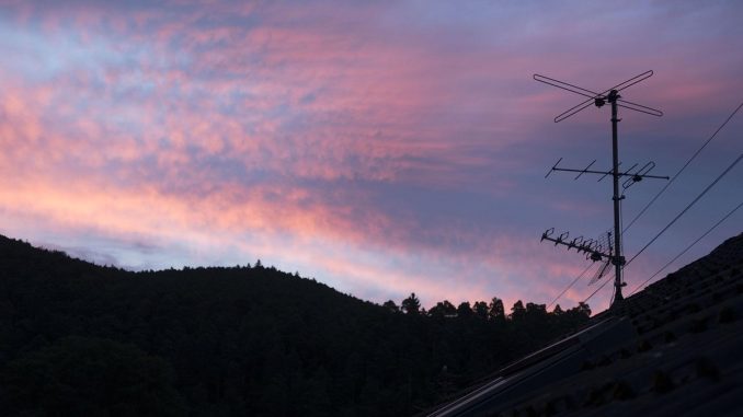 Antenne TV silhouettée contre un ciel crépusculaire rose et violet