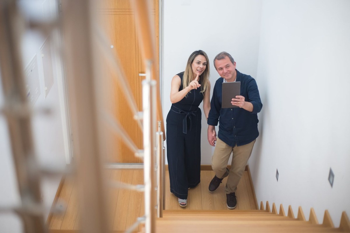 Homme et femme en bas d'un escalier, l'homme tient une tablette