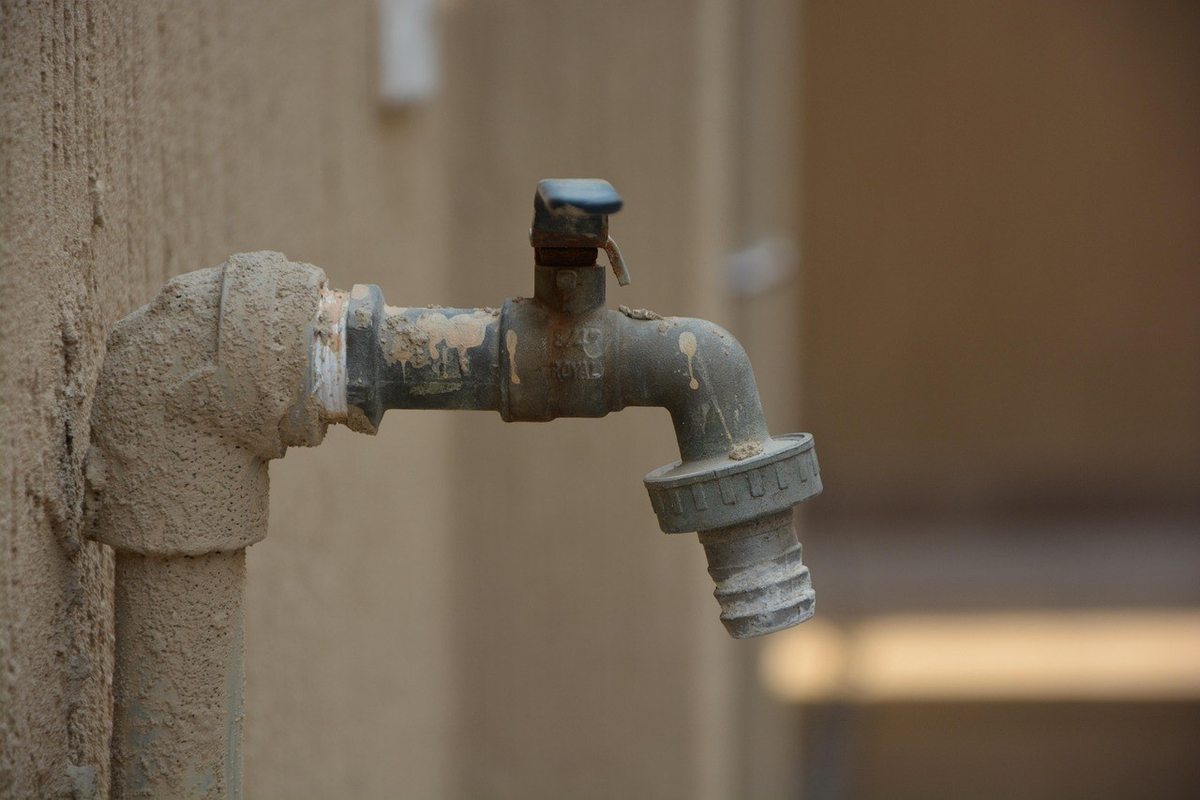 Robinet rouillé sur mur beige, tuyau d'eau, jointure, joint de plomberie, extérieur