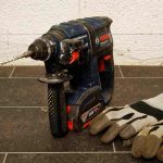 Perceuse et gants de travail sur un sol en carrelage