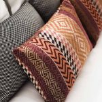 Coussins aux motifs géométriques et à carreaux disposés sur un canapé blanc
