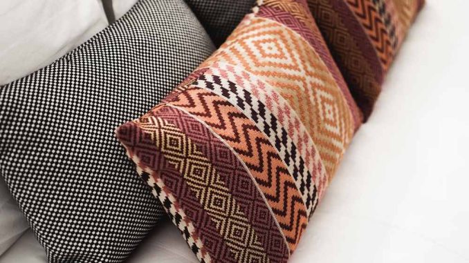 Coussins aux motifs géométriques et à carreaux disposés sur un canapé blanc